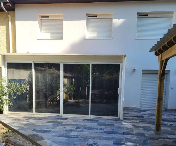 Terrasse extérieure carrelée avec dalles multicolores posée par FJ Maçonnerie devant baie vitrée à Béziers